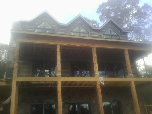 Dormers and porch framing on a large log home under construction — Roof Coating work by our crew in Hattiesburg