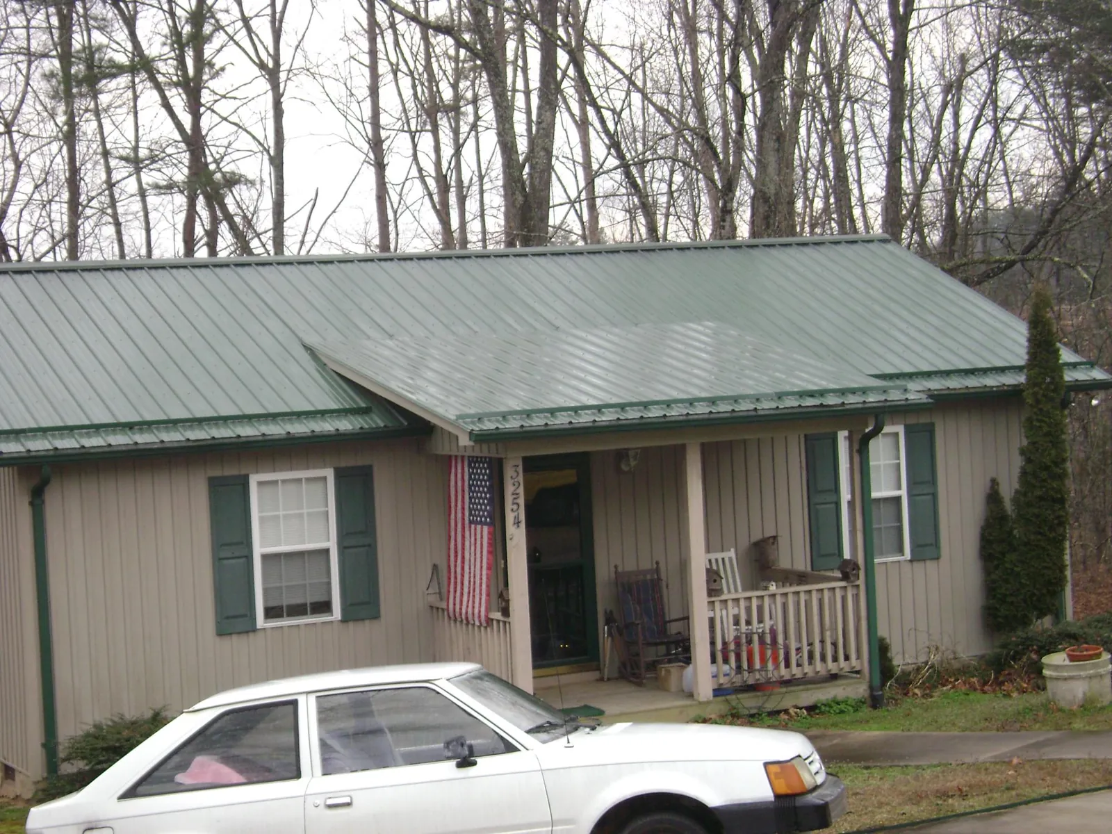 Green metal roof and front porch on a tan sided cottage in Hattiesburg
