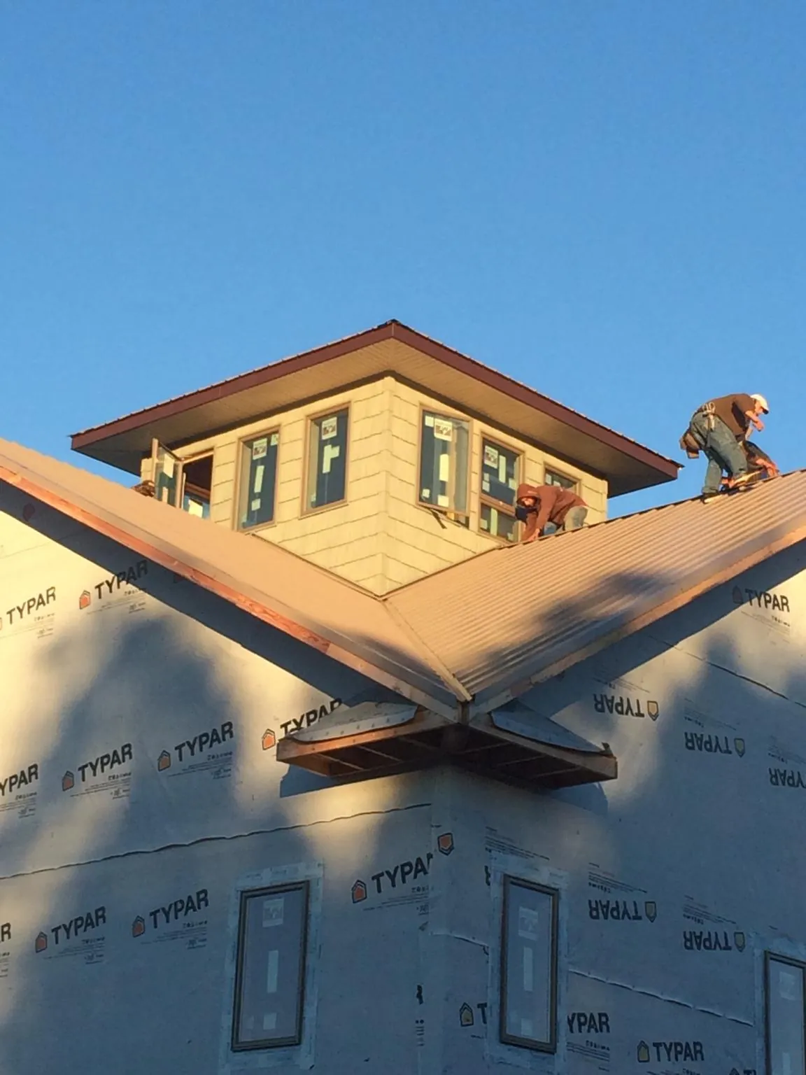Roofers working around a rooftop cupola on a new metal roof at sunset — Roof Waterproofing in Hattiesburg by Roofing Brothers